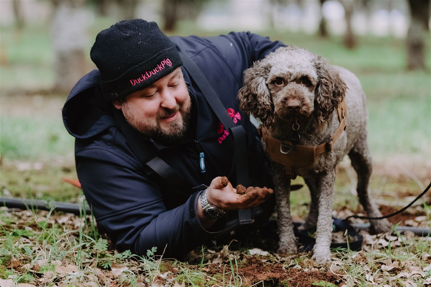 Lying in the truffle orchard holding a freshly dug truffle, next to one of the truffle dogs