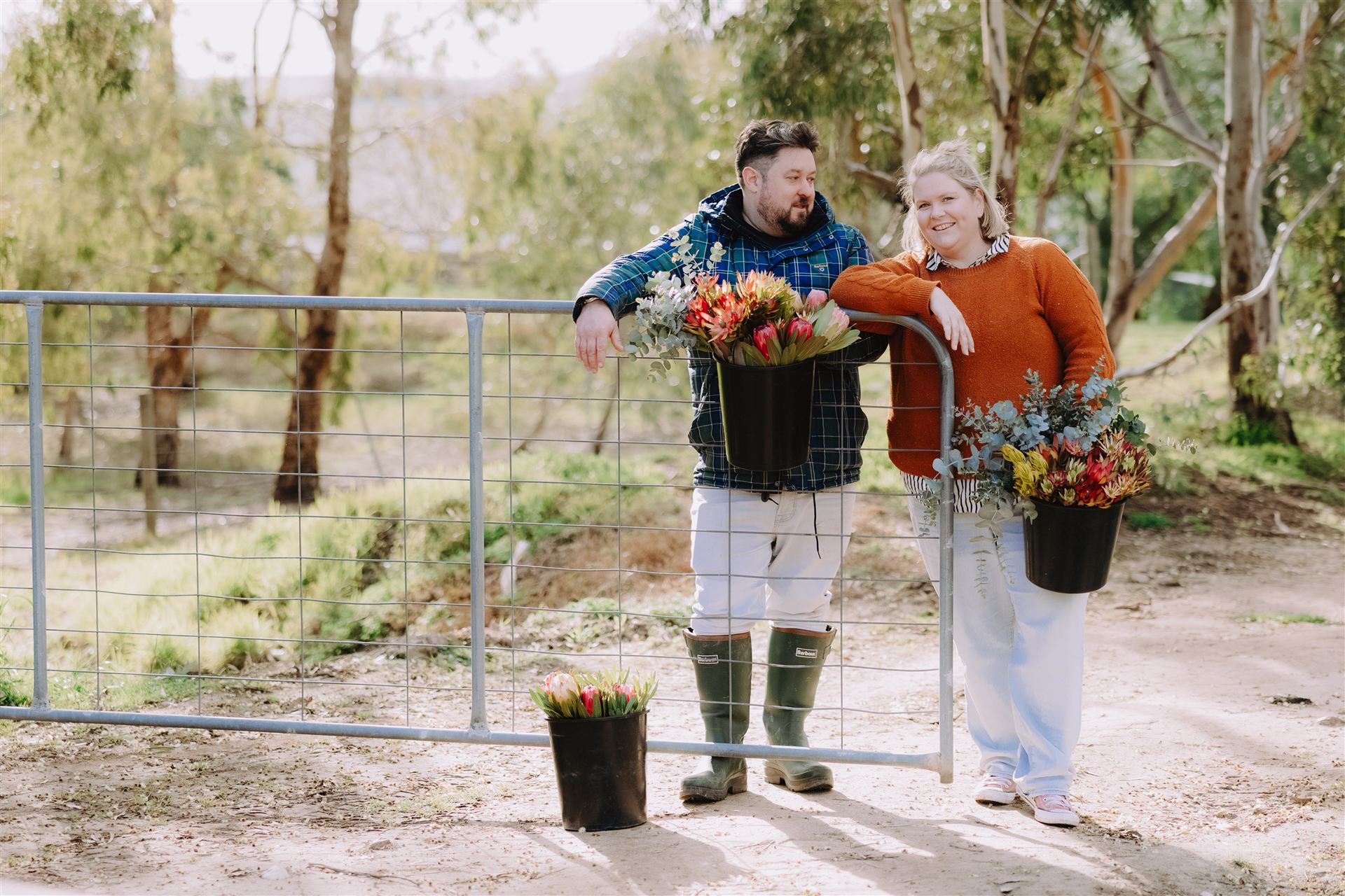 Standing at the open farm gate holding buckets of flowers