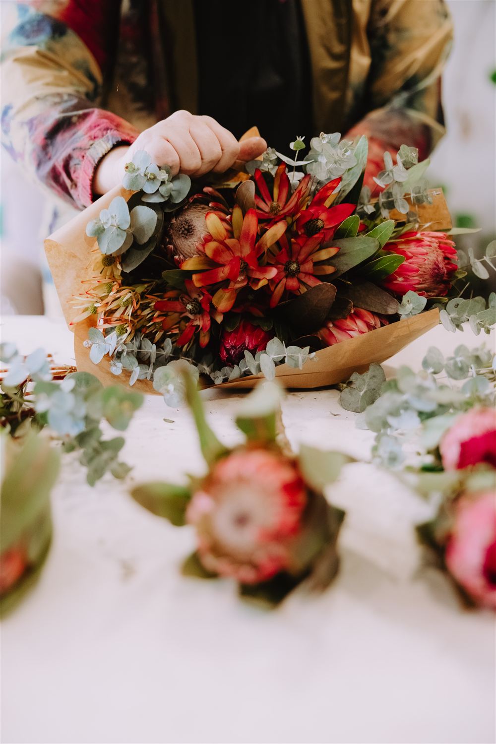 Hands arranging a bunch of native flowers at the bench